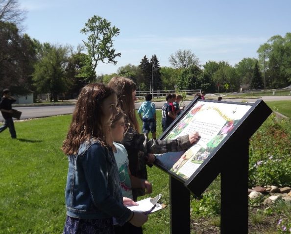 Students use a sign at the habitat to identify native plans and animals.